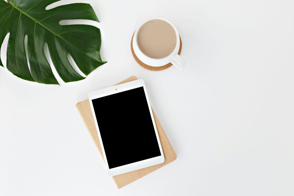 birds eye view of an ipad on a desk with a cup of tea